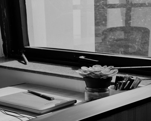 A notebook and pen resting on a desk near a window