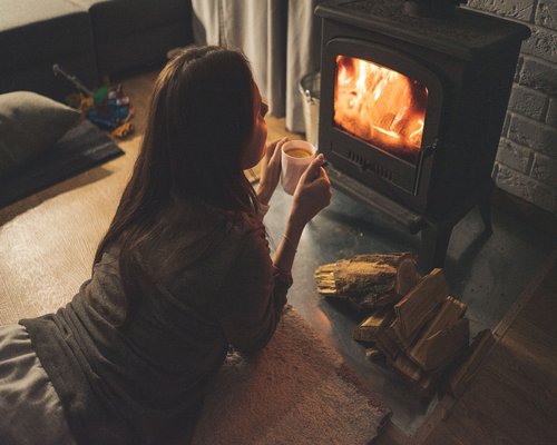 A person holding a warm cup of tea in a softly lit room